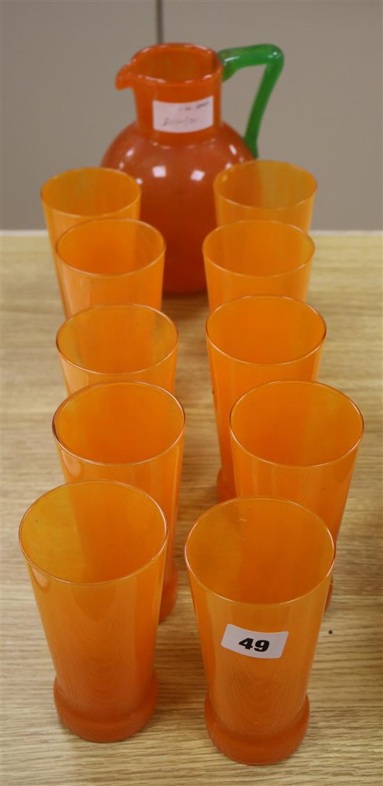 An orange and green glass jug and ten glasses
